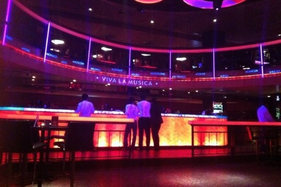 A bar with a neon sign reading "VIVA LA MUSICA" and a circular ceiling design.