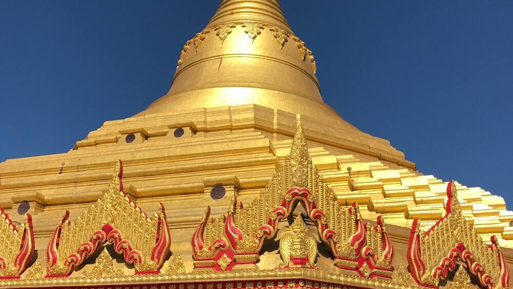 A golden stupa with intricate carvings and a pointed spire.
