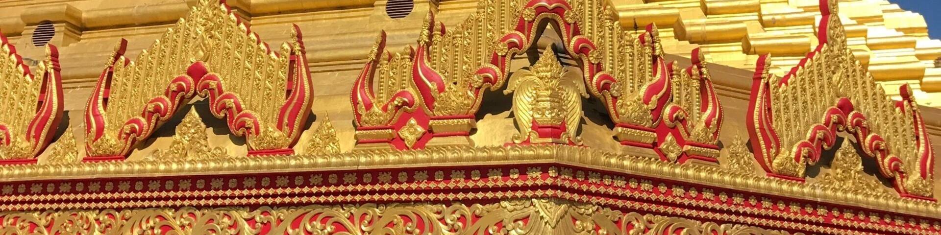 A golden stupa with intricate carvings and a pointed spire.