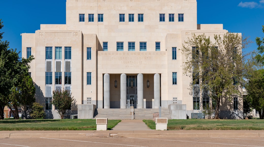 A large, beige courthouse with a central entrance flanked by columns, surrounded by a well-maintained lawn and trees.