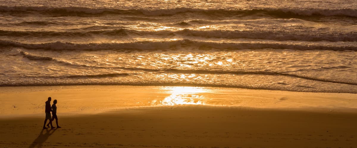 A beach with waves and a sunset.