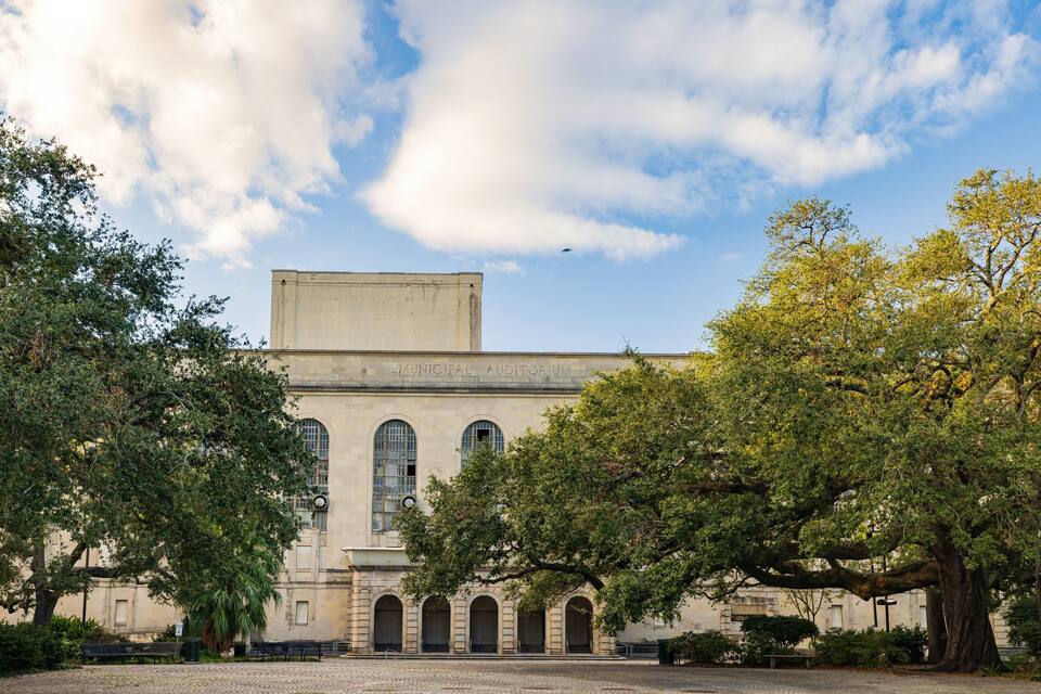 Um edifício histórico com janelas em arco e uma grande árvore em frente.