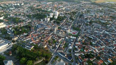 Vista aérea de uma cidade densamente povoada, com uma catedral imponente e áreas residenciais ao redor.