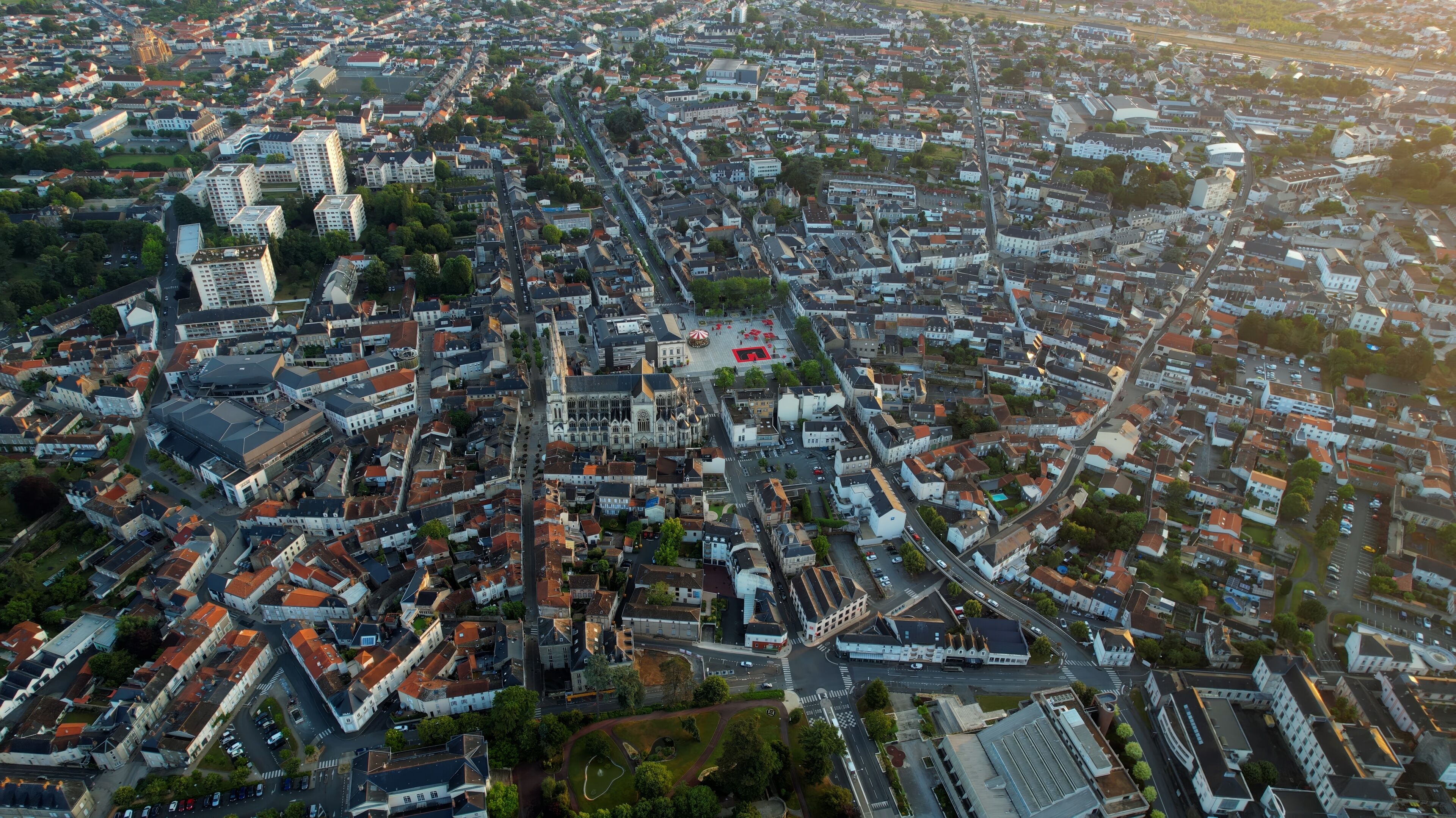 An aerial view of a densely built urban area with a prominent cathedral and a large open square.