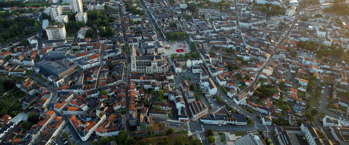 An aerial view of a densely built urban area with a prominent cathedral and a large open square.