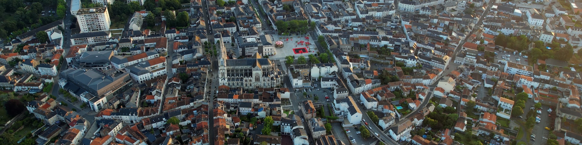 An aerial view of a densely built urban area with a prominent cathedral and a large open square.