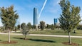 A park with trees and a tall skyscraper in the background.