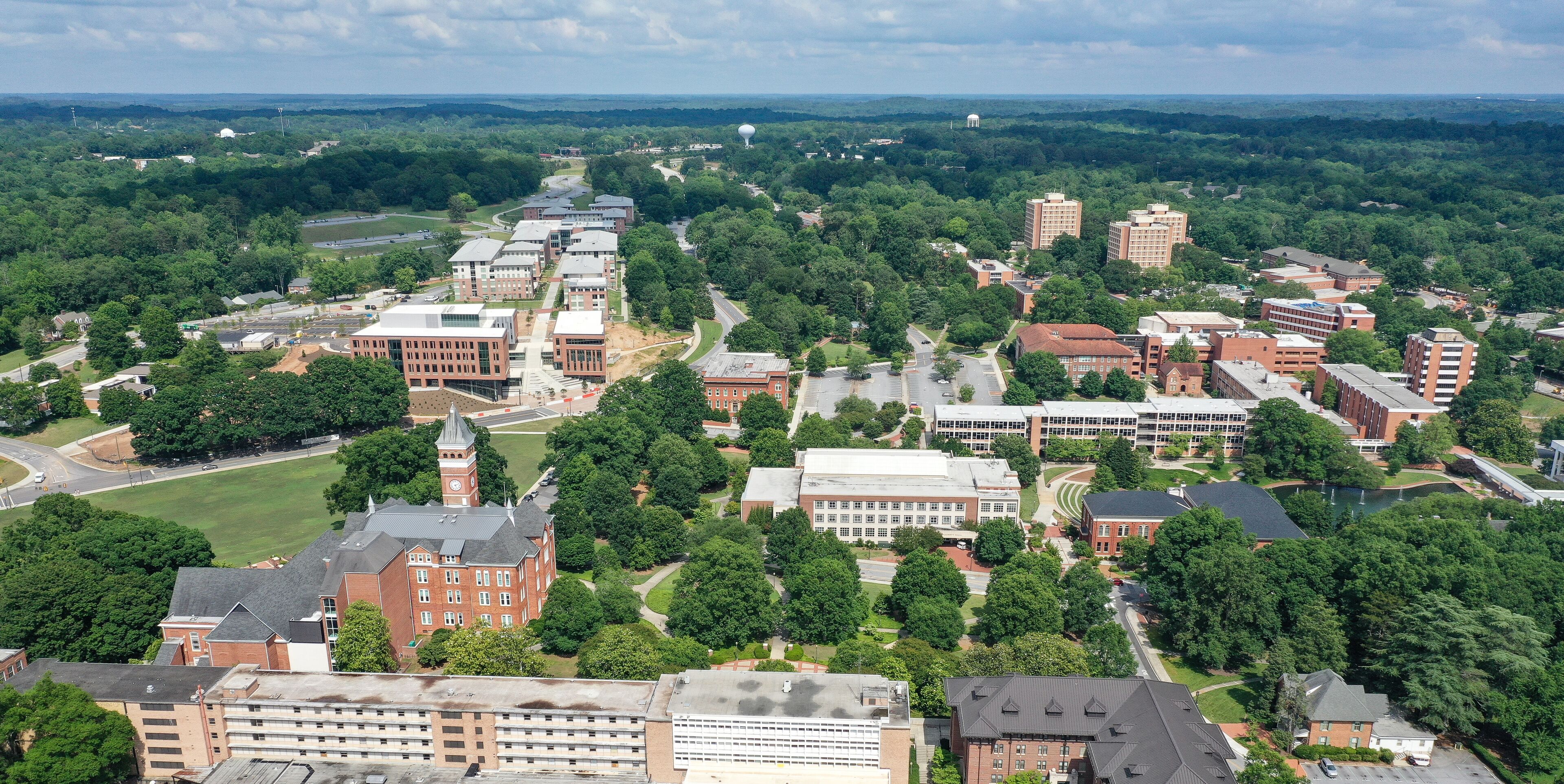 An aerial view of a university campus with multiple buildings, green spaces, and a prominent clock tower.