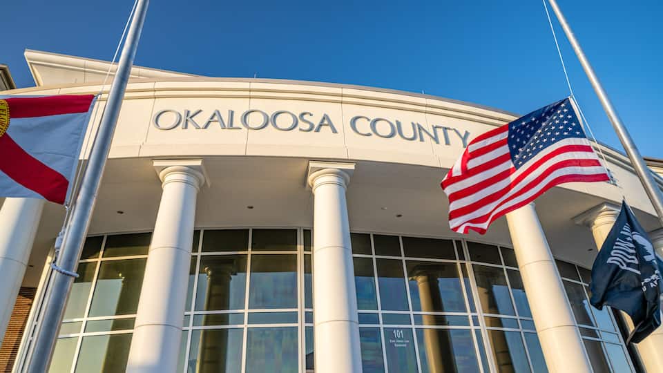 The exterior of the Oklahoma County courthouse with American flags and a state flag.
