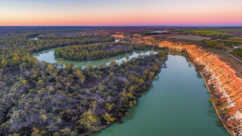A river winding through a forested area with a cliff on one side.