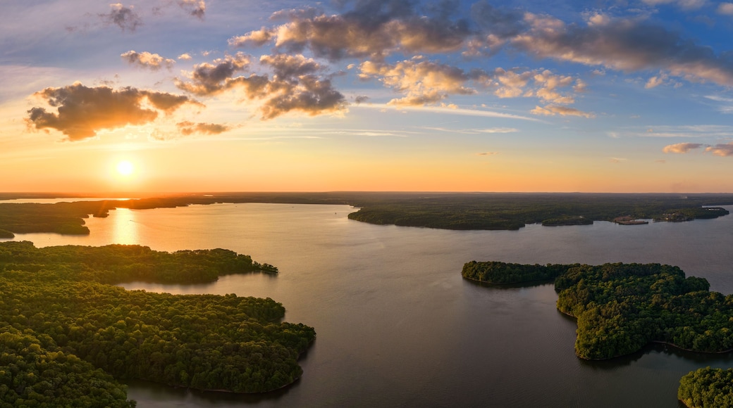 A sunset over a calm lake with several islands surrounded by dense forest.
