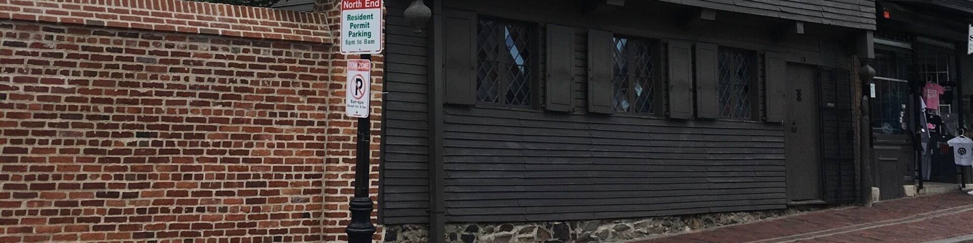 Un edificio histórico con fachada de madera oscura y una chimenea de ladrillo.