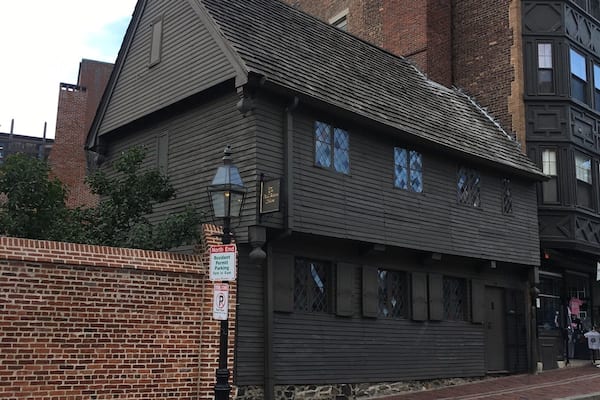 A historic building with a dark wooden facade and a brick chimney.
