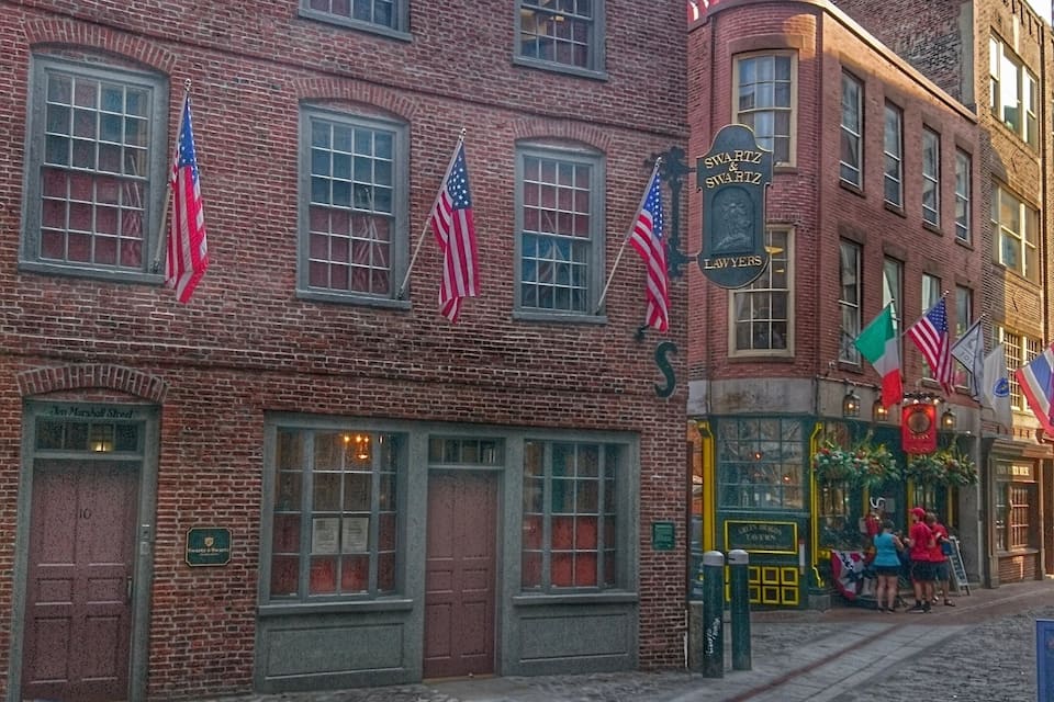 A brick building with multiple American flags, a sign reading "Swartz & Swartz Lawyers," and a storefront with a green awning.