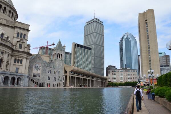 A cityscape with a historic building, a modern skyscraper, and a river.