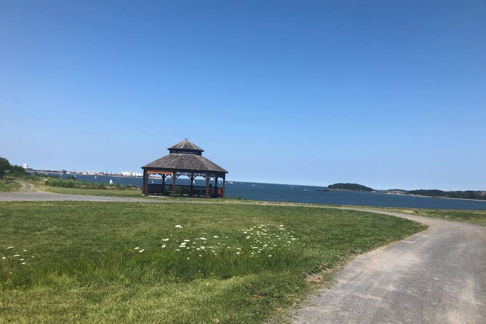 Un belvédère situé au bord d’une route côtière, sous un ciel bleu dégagé.
