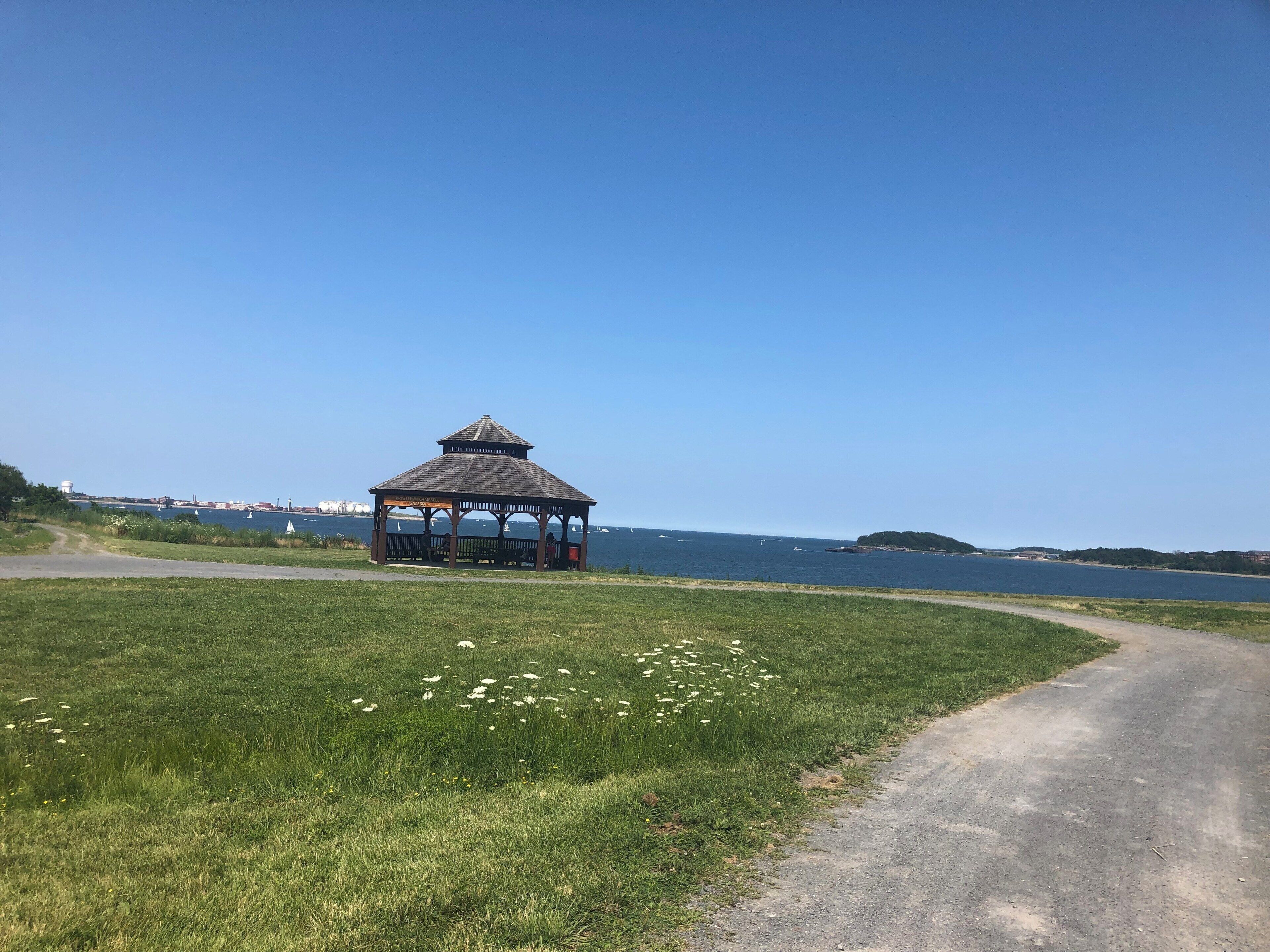 A gazebo by a coastal road with a clear blue sky.