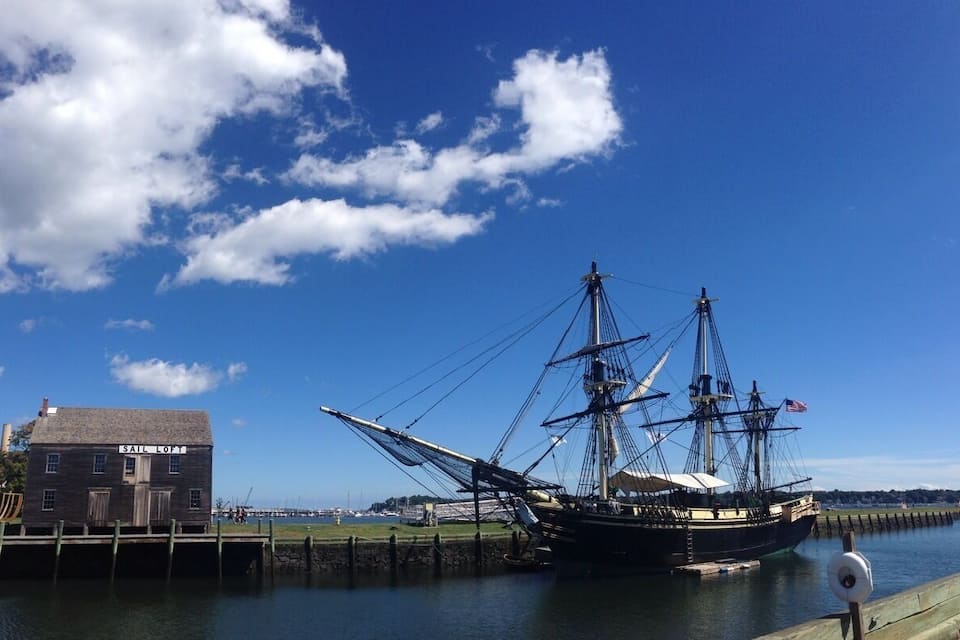 A historic sailing ship docked at a pier with a building labeled "Sail Loft" nearby.