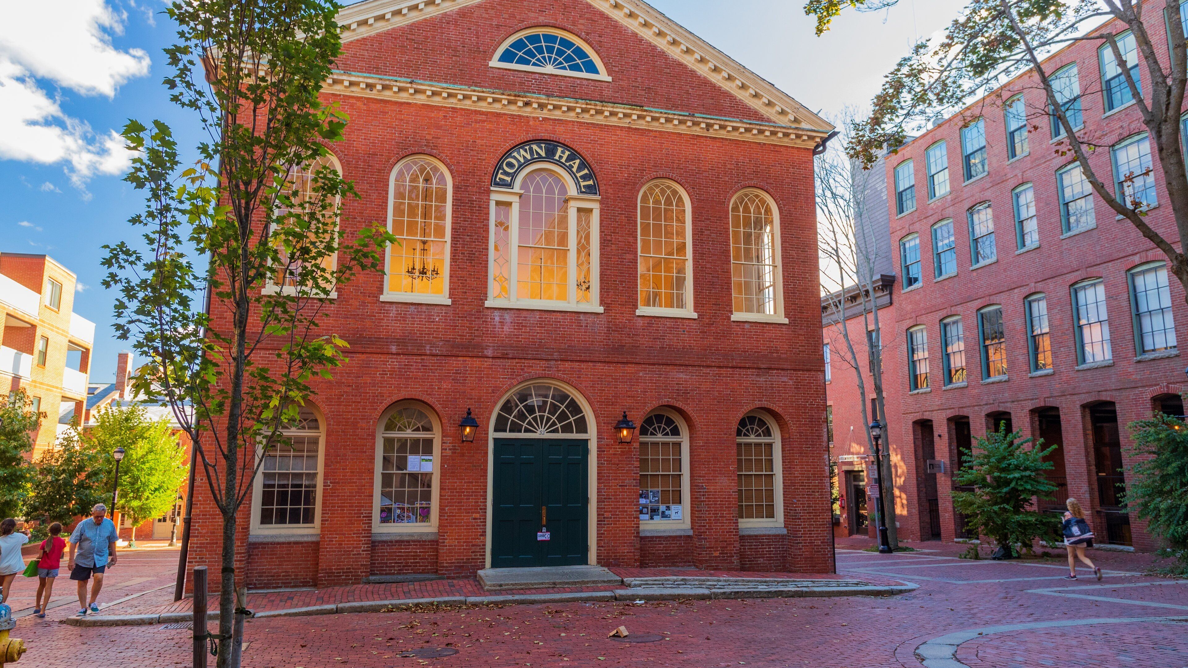 A red brick building with arched windows and a Town Hall sign.