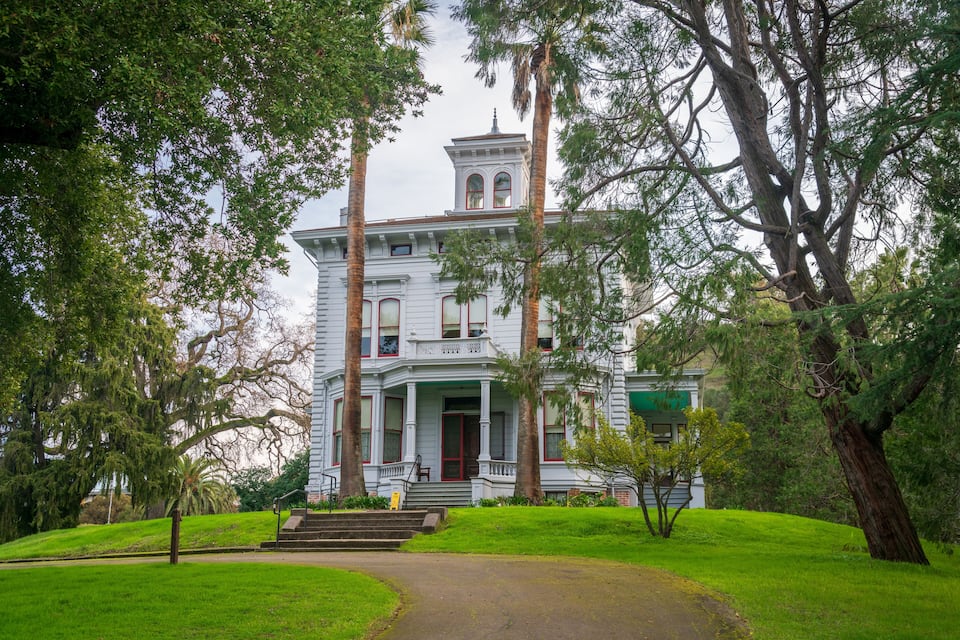 A large white building with a tower, surrounded by trees and a grassy area.