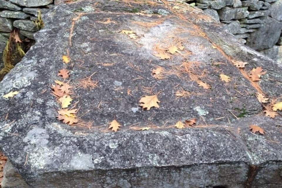 A large stone structure surrounded by autumn leaves.