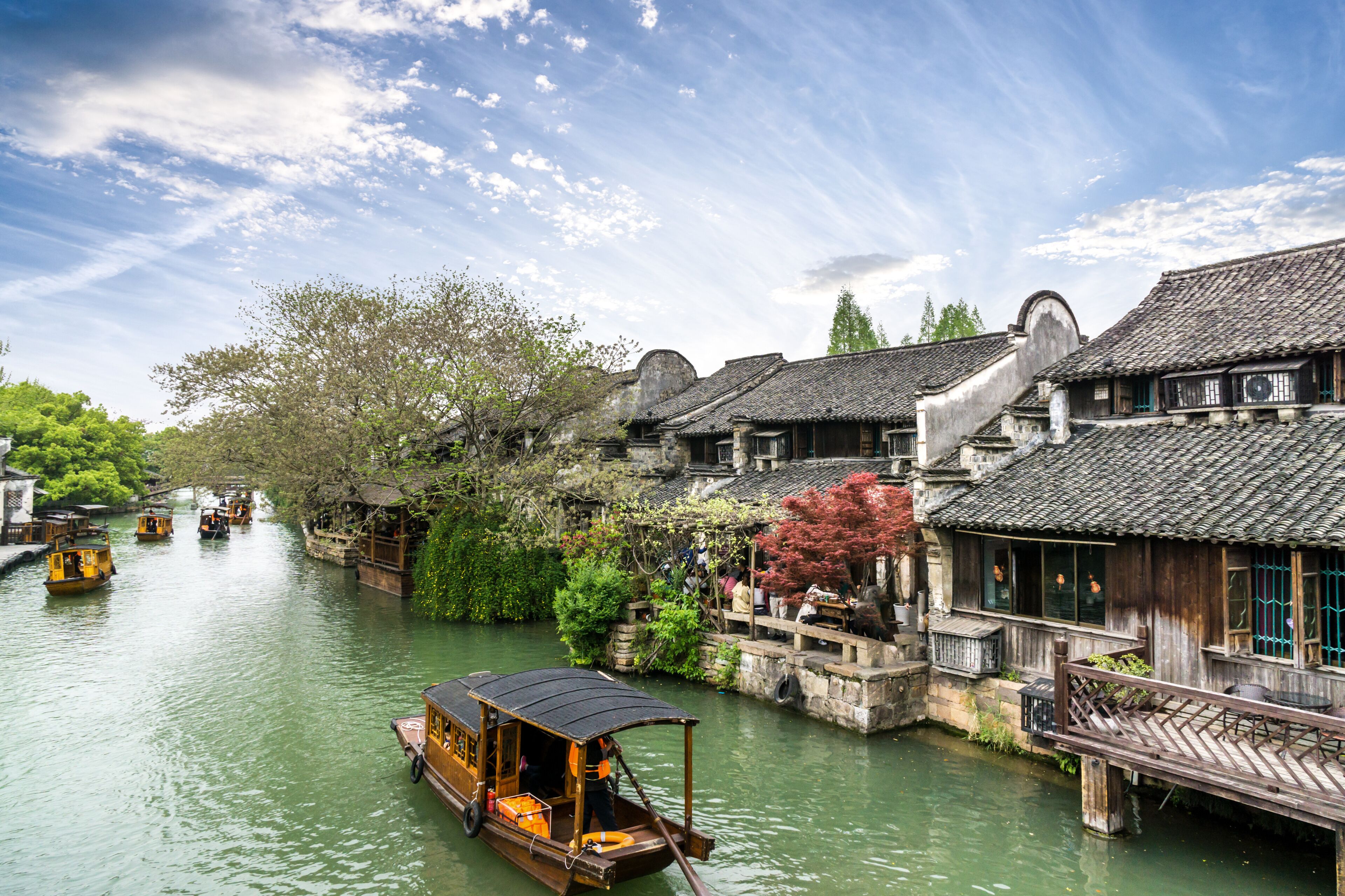 A traditional wooden boat on a river, surrounded by historic buildings with tiled roofs.