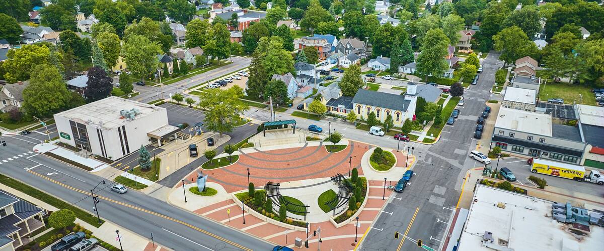 An aerial view of a town with a roundabout, residential houses, and a church.
