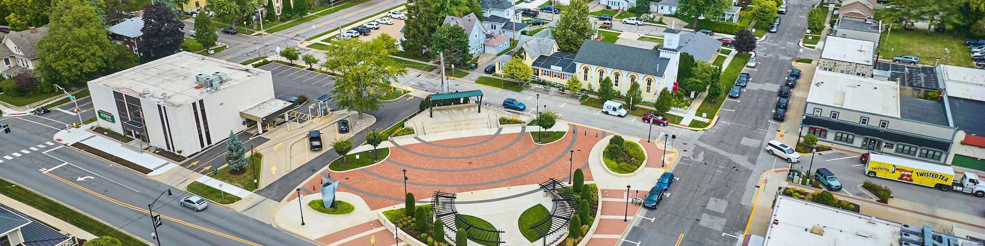 An aerial view of a town with a roundabout, residential houses, and a church.