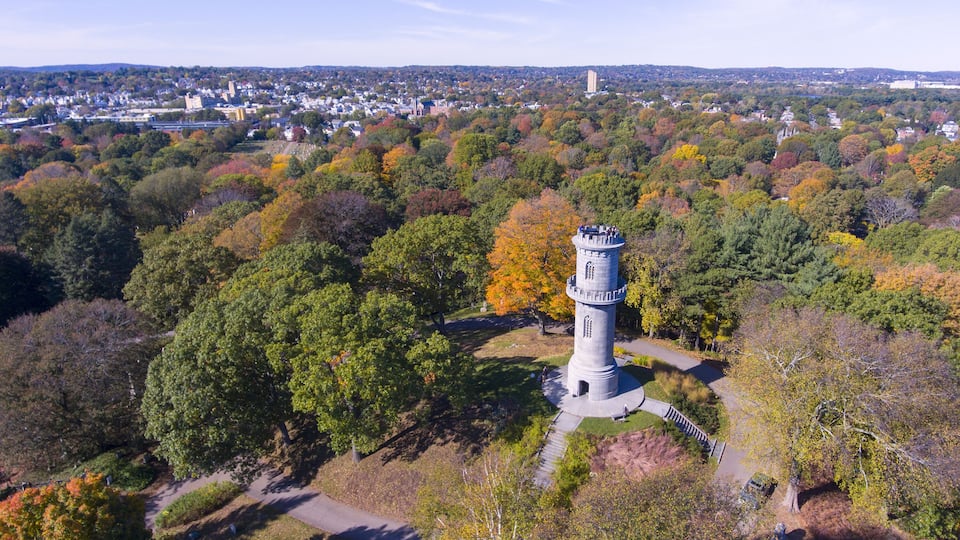 A tower amidst autumn foliage, surrounded by a park with a clear sky.