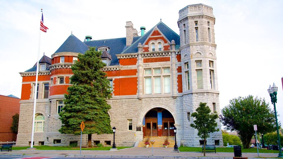 A historic building with a large tree in front, a flagpole with an American flag, and a stone tower.