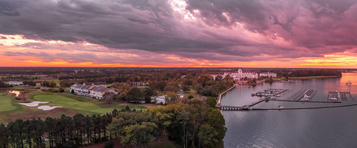 A golf course, a large building complex, and a marina by a river.