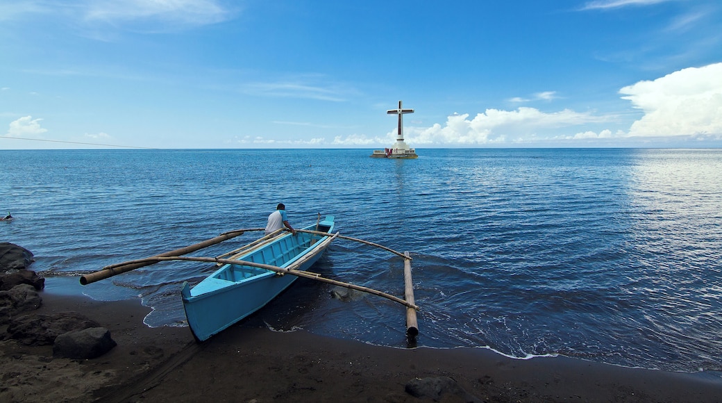 A local pushes his boat to the open sea towards the lone, conspicuous cross that marks the old cemetery of Camiguin island that was sunk in one of the island volcano's eruption more than a century ago.