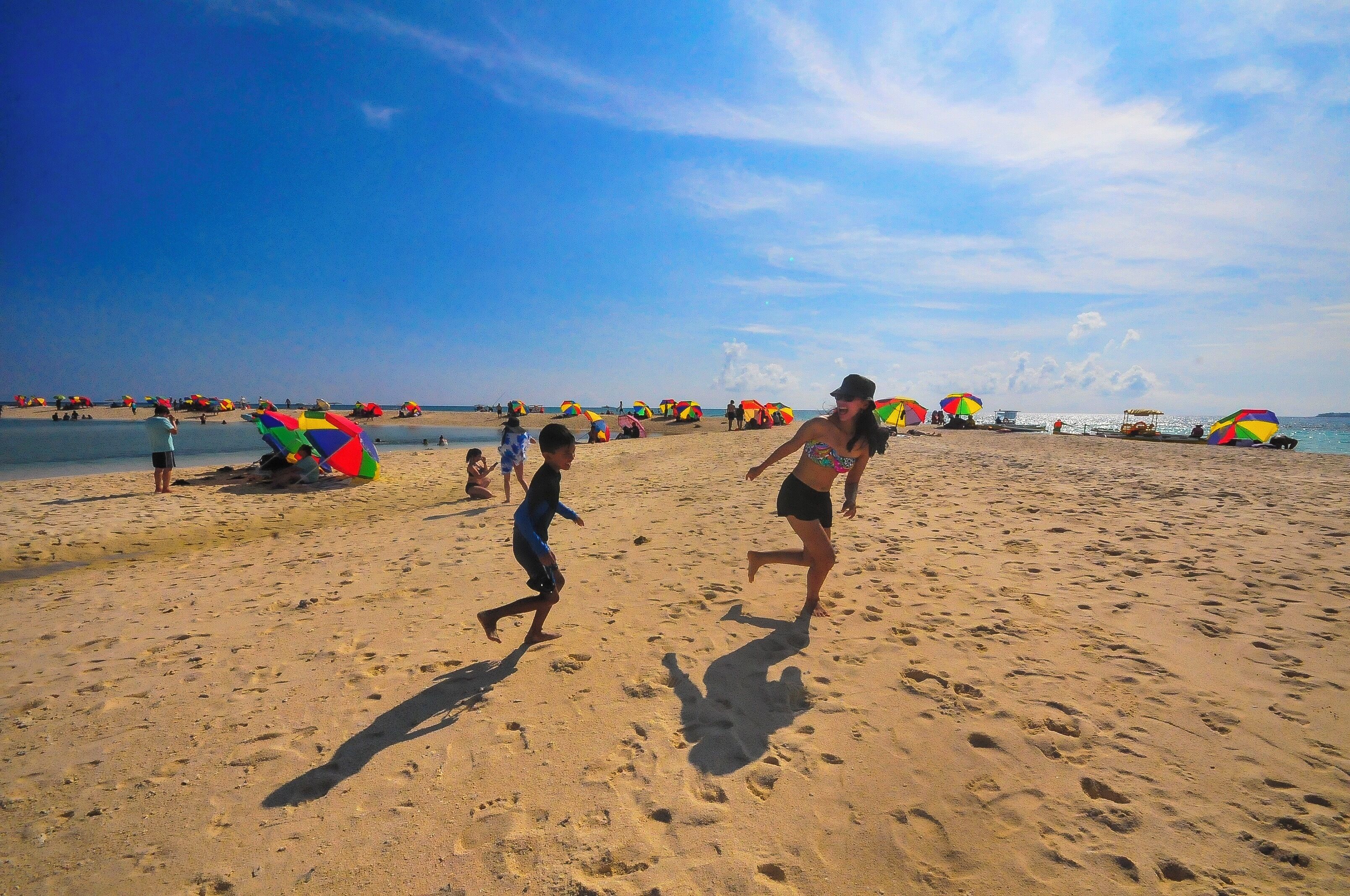 Una playa arenosa con sombrillas de colores y huellas en la arena.