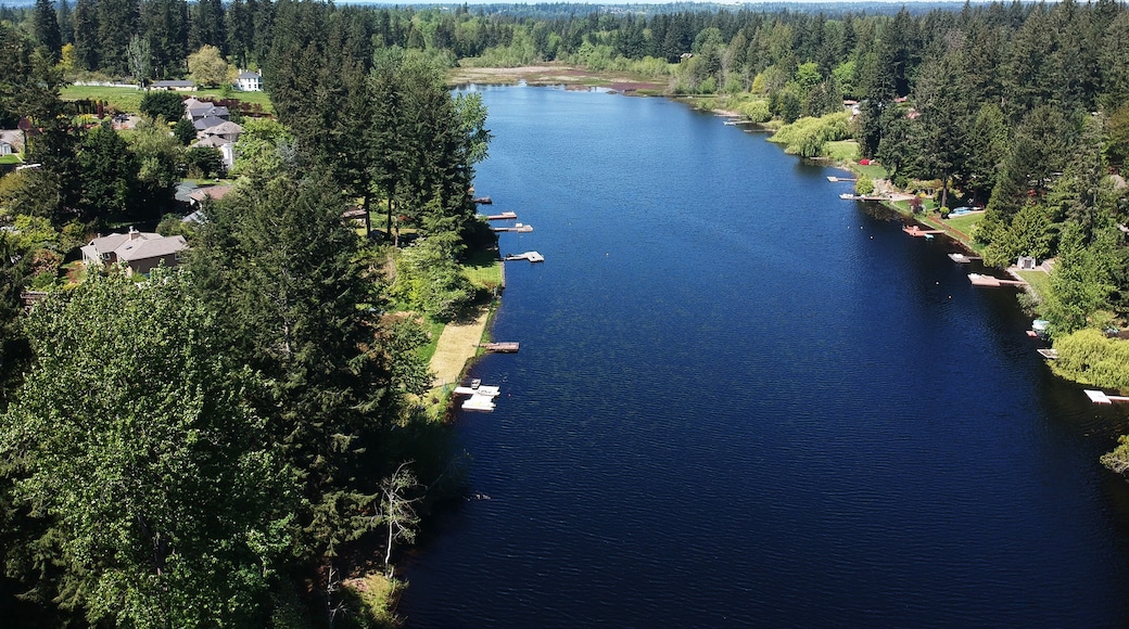 Lovely Lake Holm Water Access Site in springtime with the surrounding forest and homes and the sky and clouds in Auburn Washington