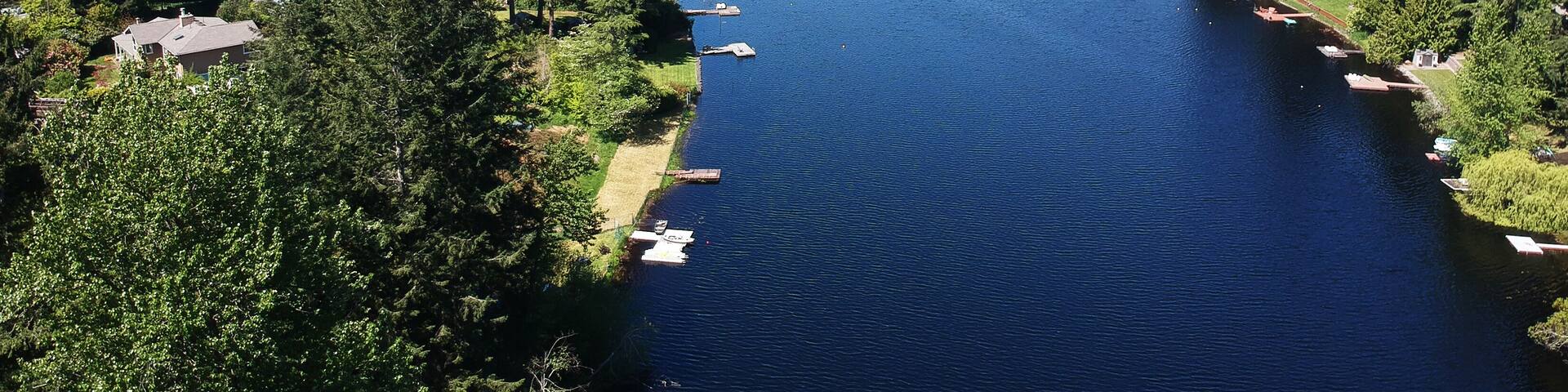 Lovely Lake Holm Water Access Site in springtime with the surrounding forest and homes and the sky and clouds in Auburn Washington