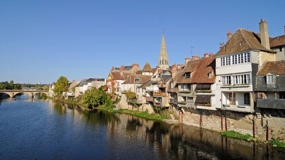 A river with a bridge, historic buildings, and a church spire.