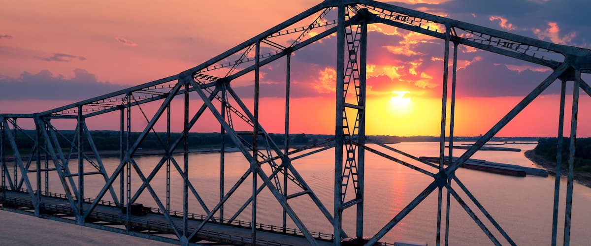 A steel bridge with a sunset in the background.