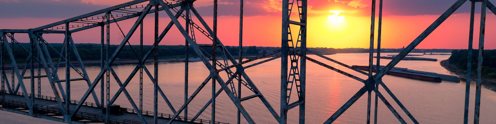 A steel bridge with a sunset in the background.