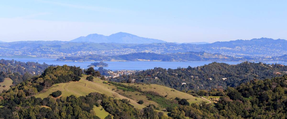 A coastal landscape with a mountain range, a lake, and a town in the valley.