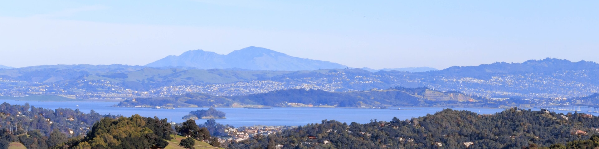 A coastal landscape with a mountain range, a lake, and a town in the valley.