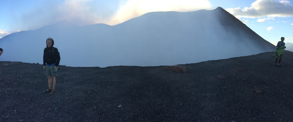 A volcanic landscape with a large, steep-sided mountain in the background.