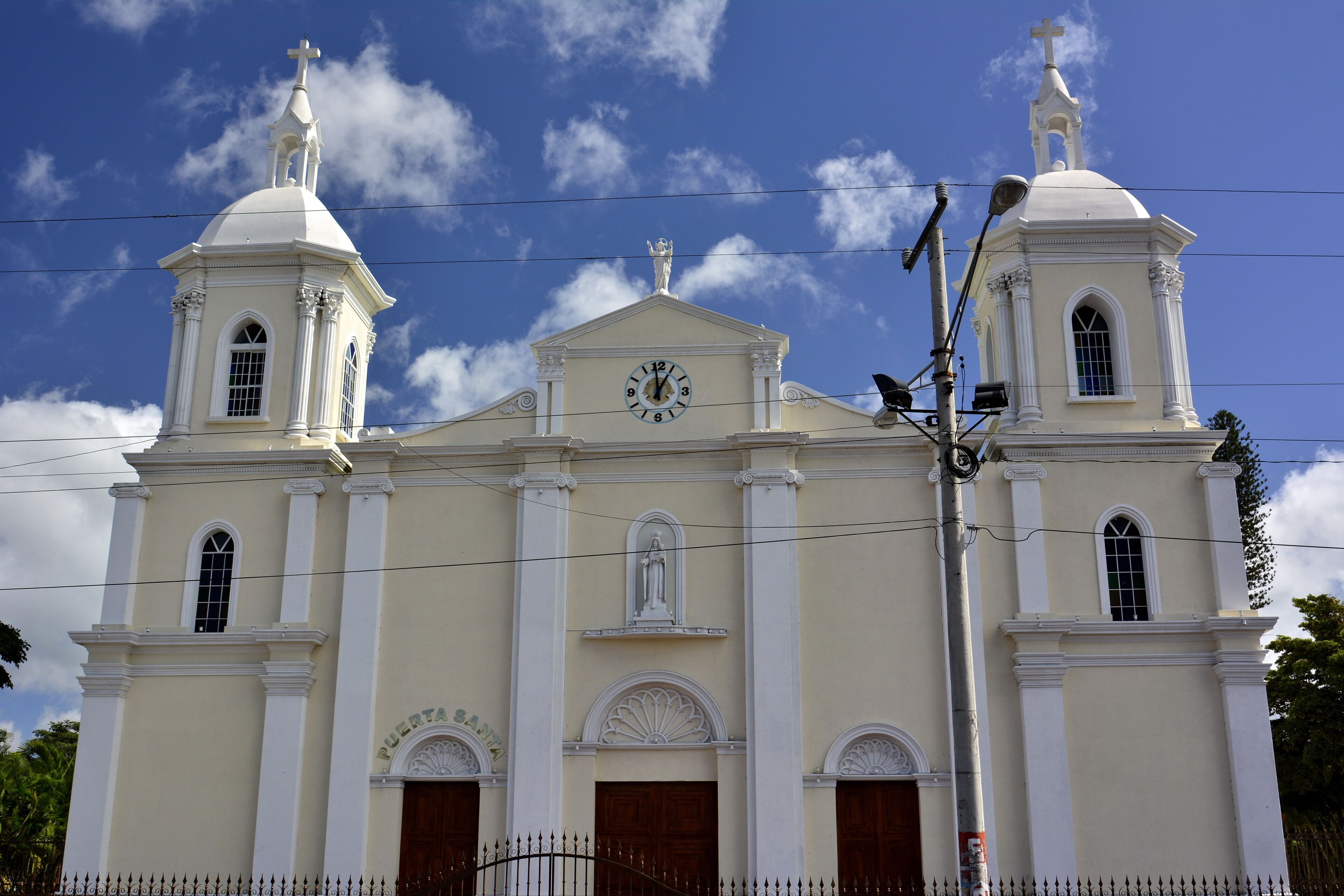 A church with two towers, a clock, and a statue on the roof.