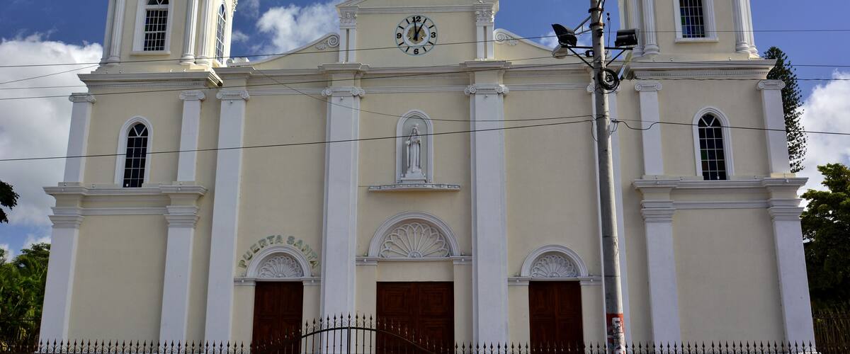 A church with two towers, a clock, and a statue on the roof.