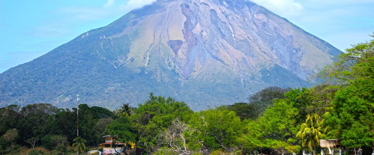 A mountain with a visible crater, surrounded by lush greenery and a small building labeled "HOTEL".