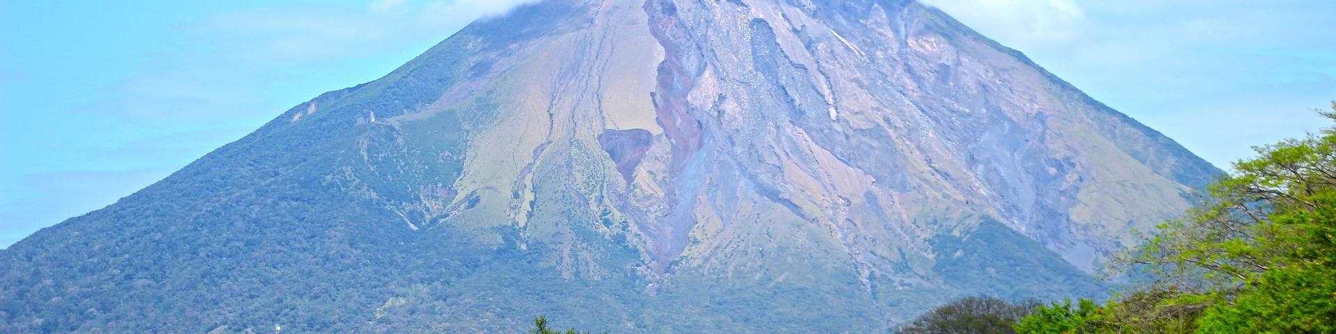 A mountain with a visible crater, surrounded by lush greenery and a small building labeled "HOTEL".