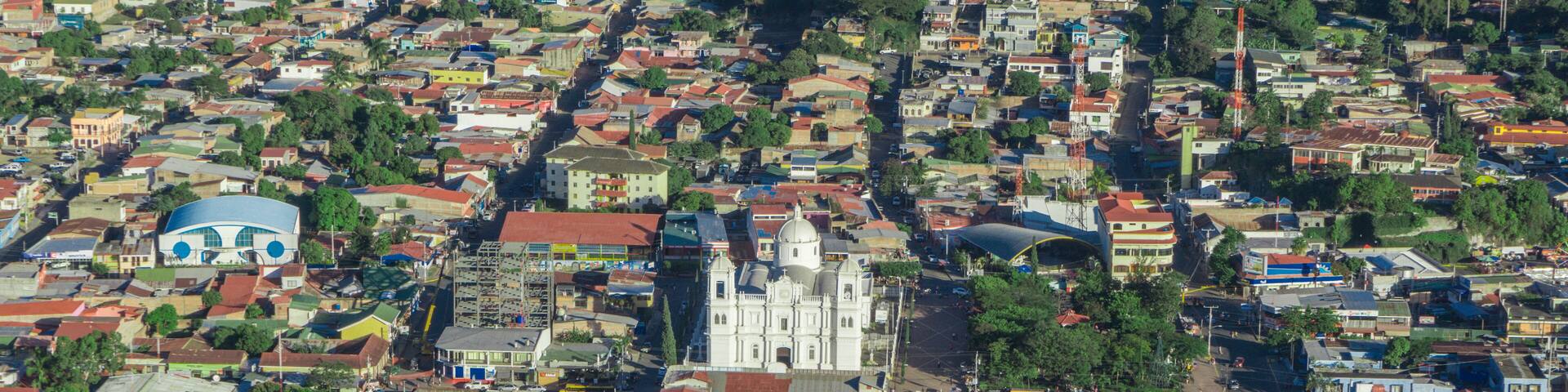 incredible aerial view of city surrounded by forest and mountains