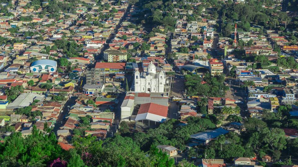 incredible aerial view of city surrounded by forest and mountains