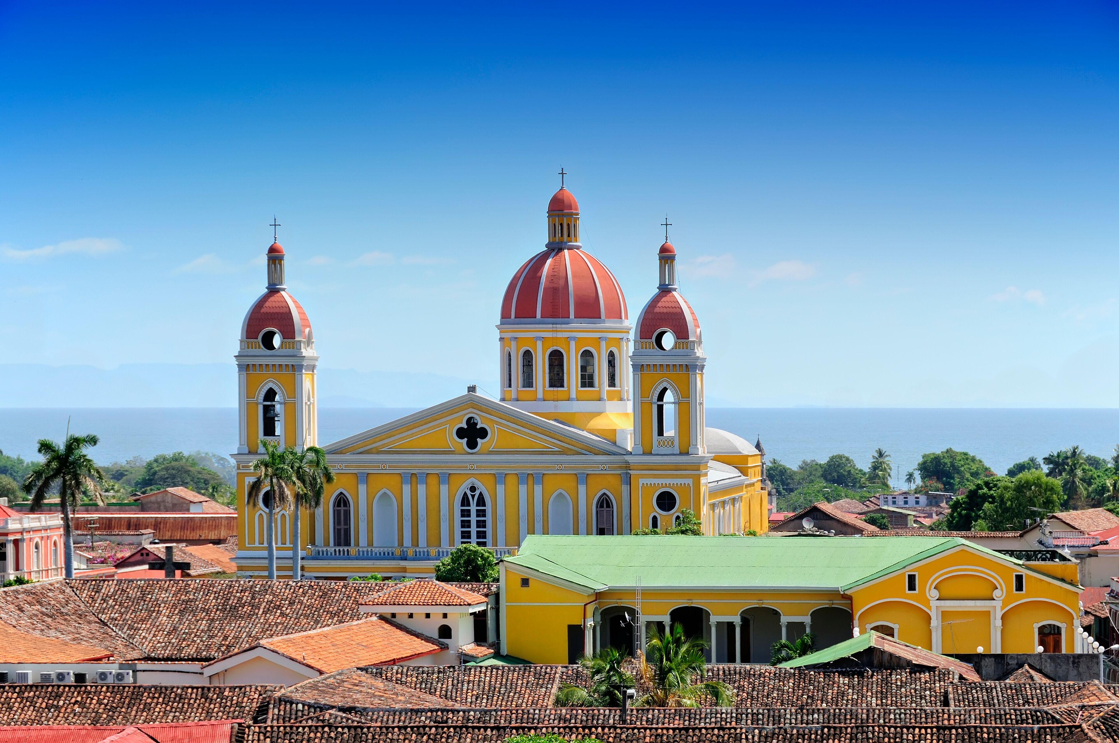 A yellow church with two red domes and a green-roofed building in the foreground.
