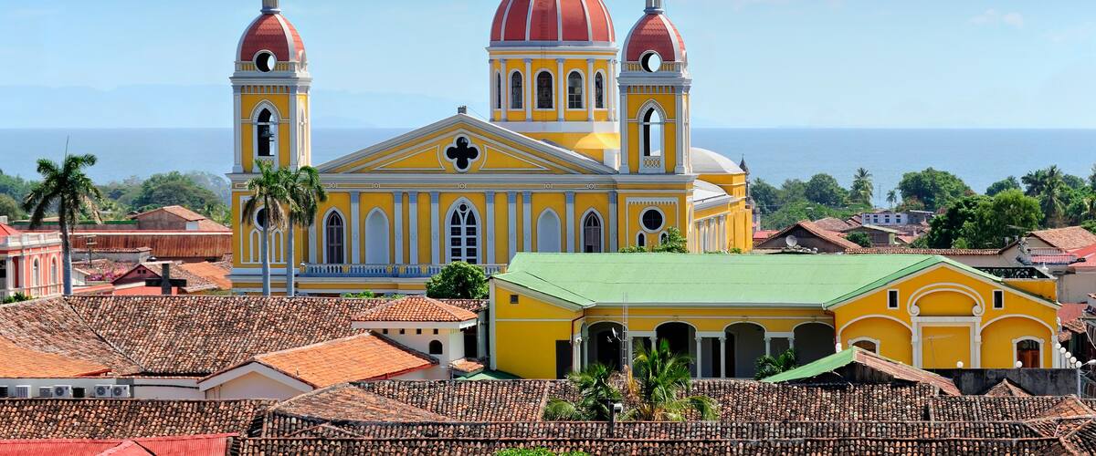 A yellow church with two red domes and a green-roofed building in the foreground.