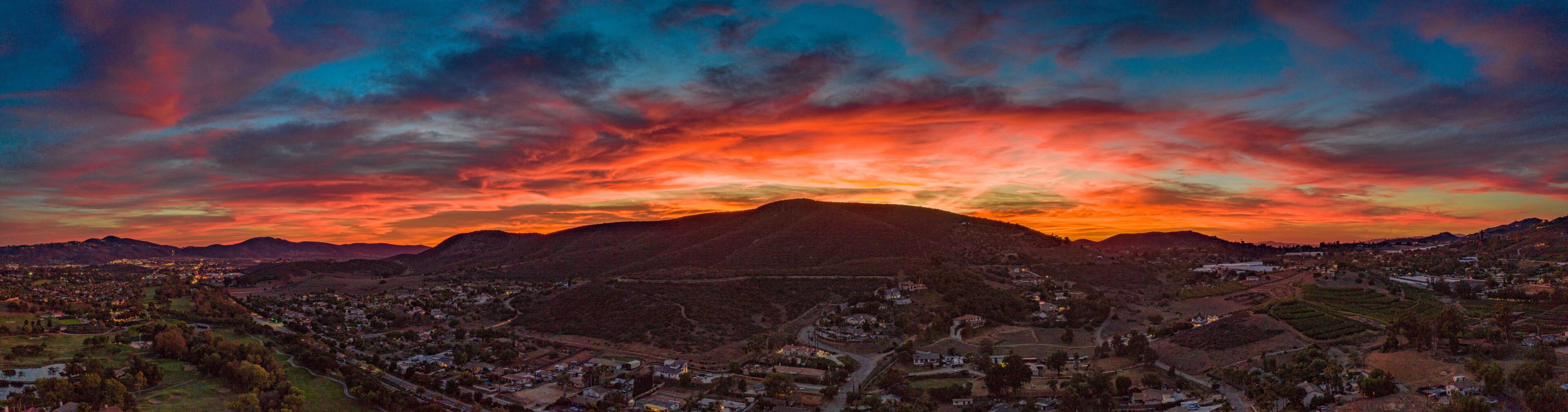 A sunset over a mountainous landscape with a town in the foreground.